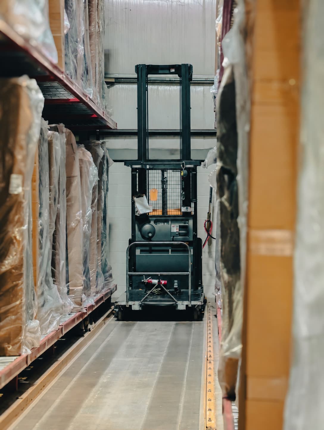 A warehouse aisle with an order picker between the racks.